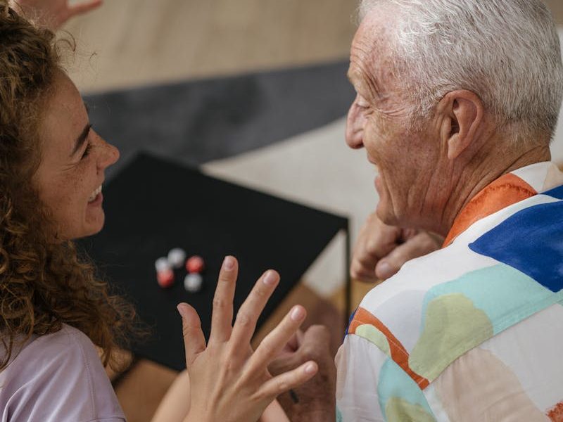Elderly man and woman engaged in a joyful indoor conversation, emphasizing connection and happiness.